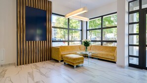 A modern lobby with a yellow sofa, a glass coffee table, and a wooden accent wall.