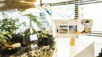 A glass terrarium with plants, a wooden sign, and a brochure on a table.