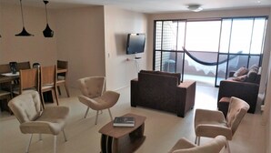 Una sala moderna con un sofá, sillones, una mesa de centro y un comedor con sillas y una mesa.
