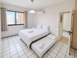 A hotel room with a bed, a window with curtains, an air conditioning unit, and a tiled floor. - Apartamento a 200m feirinha beira mar (Fortaleza)