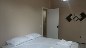 Una habitación de hotel con cama, almohadas y una puerta.