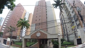 Un edificio a più piani con un ingresso chiuso da cancello, circondato da palme e altra vegetazione.