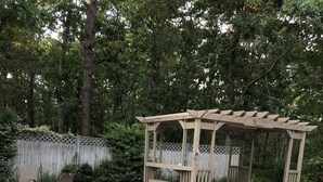 En terrasse med pergola, to stole og et bålsted.