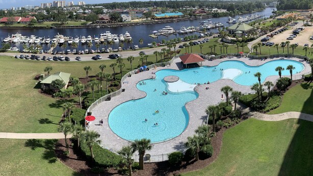 Een groot waterpark met meerdere zwembaden en een jachthaven op de achtergrond.