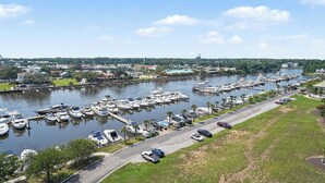 A marina with boats docked, a road alongside, and a water tower in the distance.