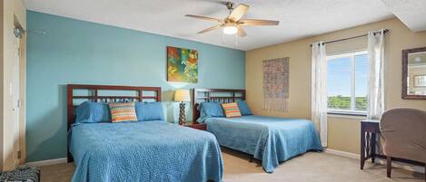 A hotel room with two beds, a ceiling fan, a painting, and a window with curtains.