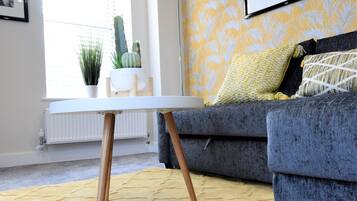 A living room with a sofa, a table, and a lamp.