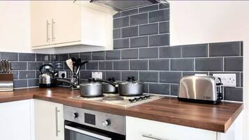 A modern kitchen with a wooden countertop, stainless steel appliances, and black and white tiled backsplash.