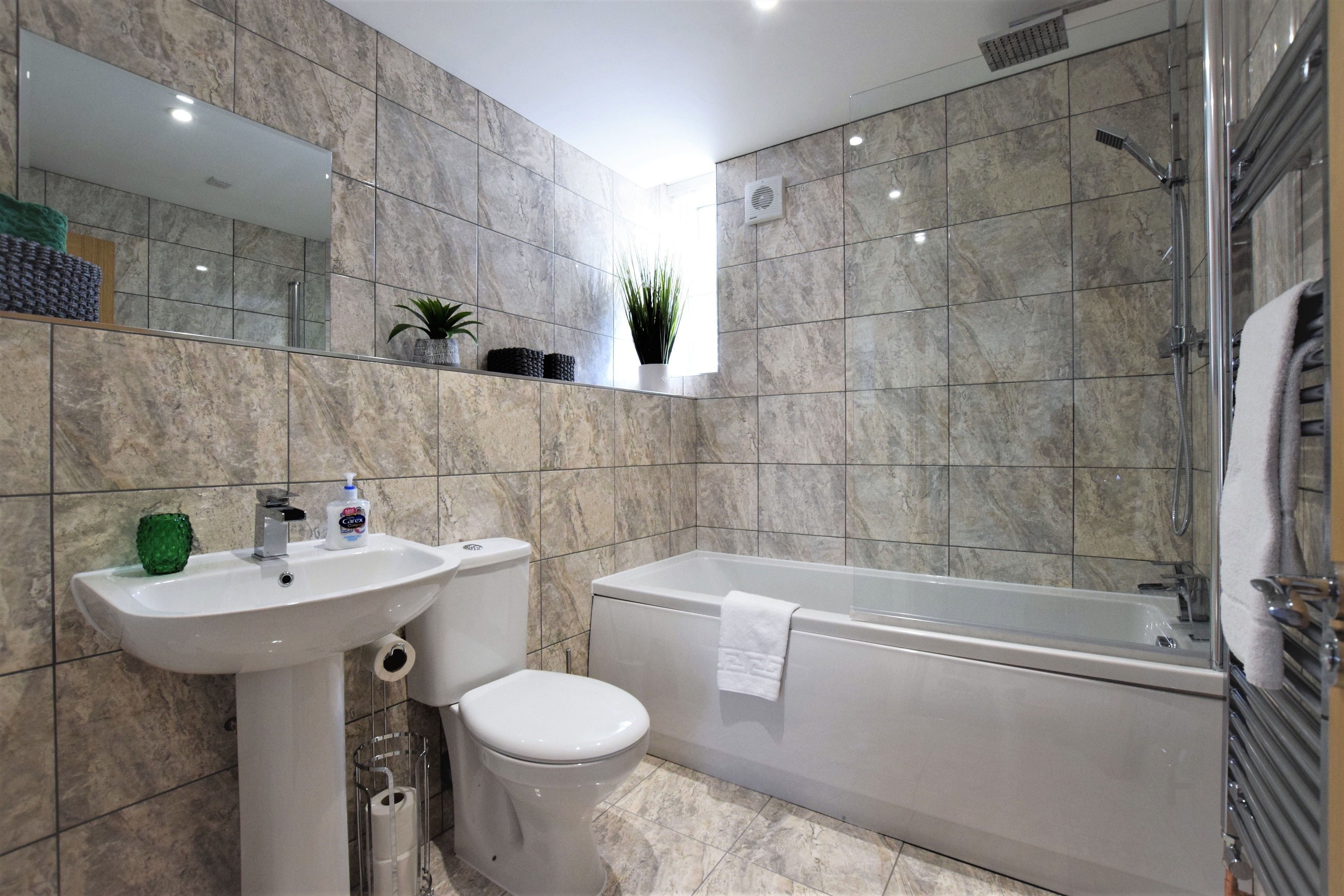 A modern bathroom with a sink, toilet, and bathtub.