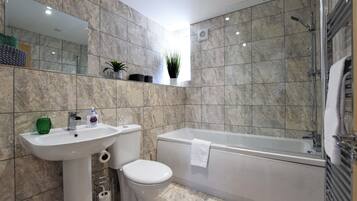 A modern bathroom with a sink, toilet, and bathtub.