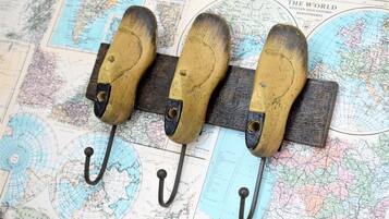 A wooden pegboard with three metal hooks against a background of old maps.