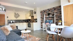 A modern living room with a sofa, coffee table, and dining area. - The Old Bank - yourapartment (Bristol)