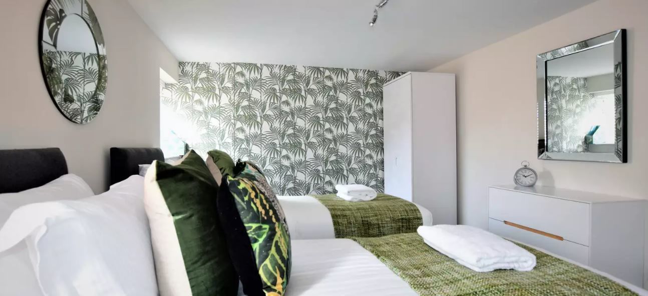 Ein Hotelzimmer mit zwei Betten, einem Schrank, einem Spiegel und einem Wandteppich.