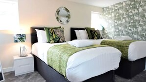 A double bed with a green and white bedspread, a nightstand with a lamp, and a mirror. - The Old Bank - yourapartment (Bristol)