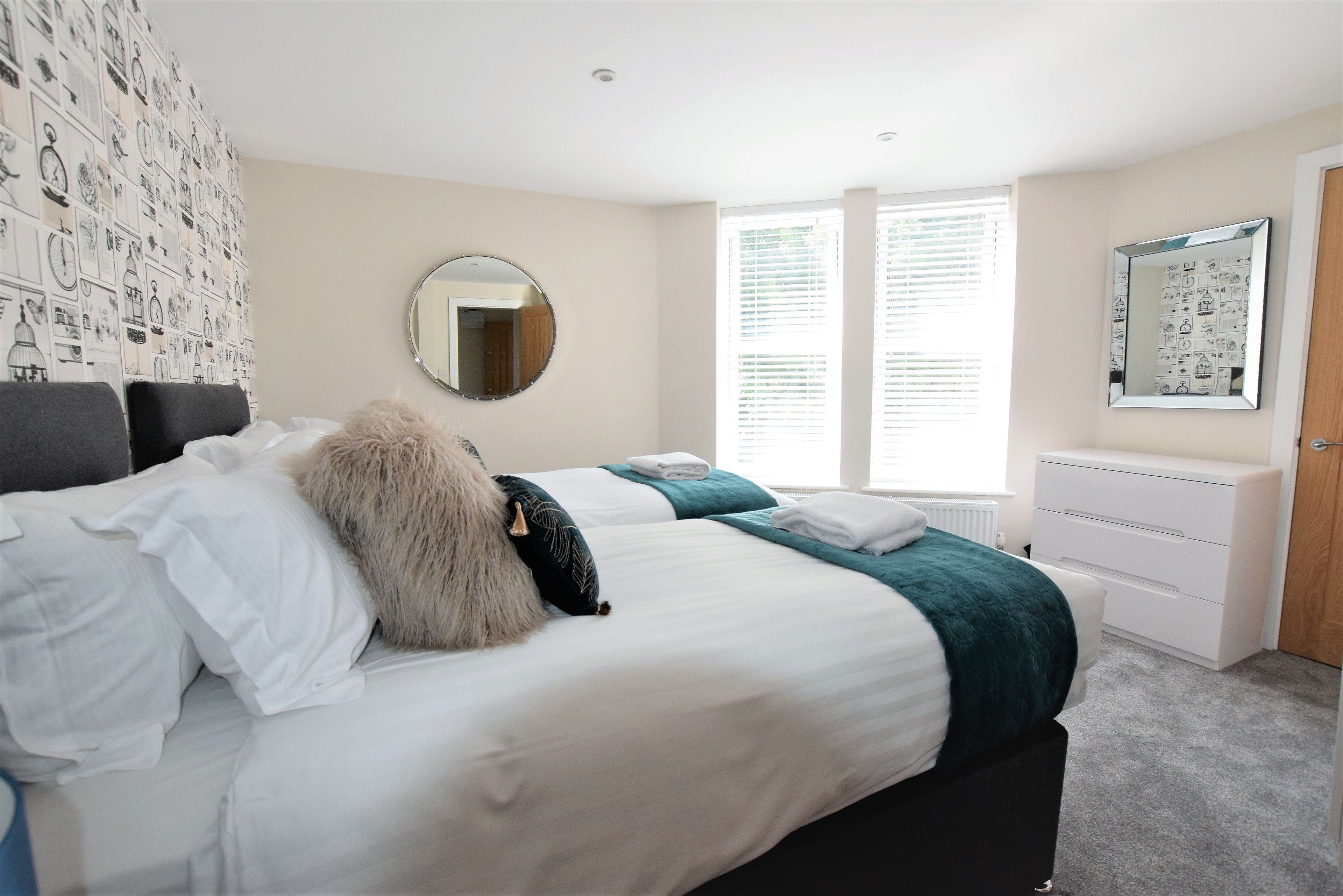 A bedroom with a bed, a dresser, a mirror, and a window with blinds.