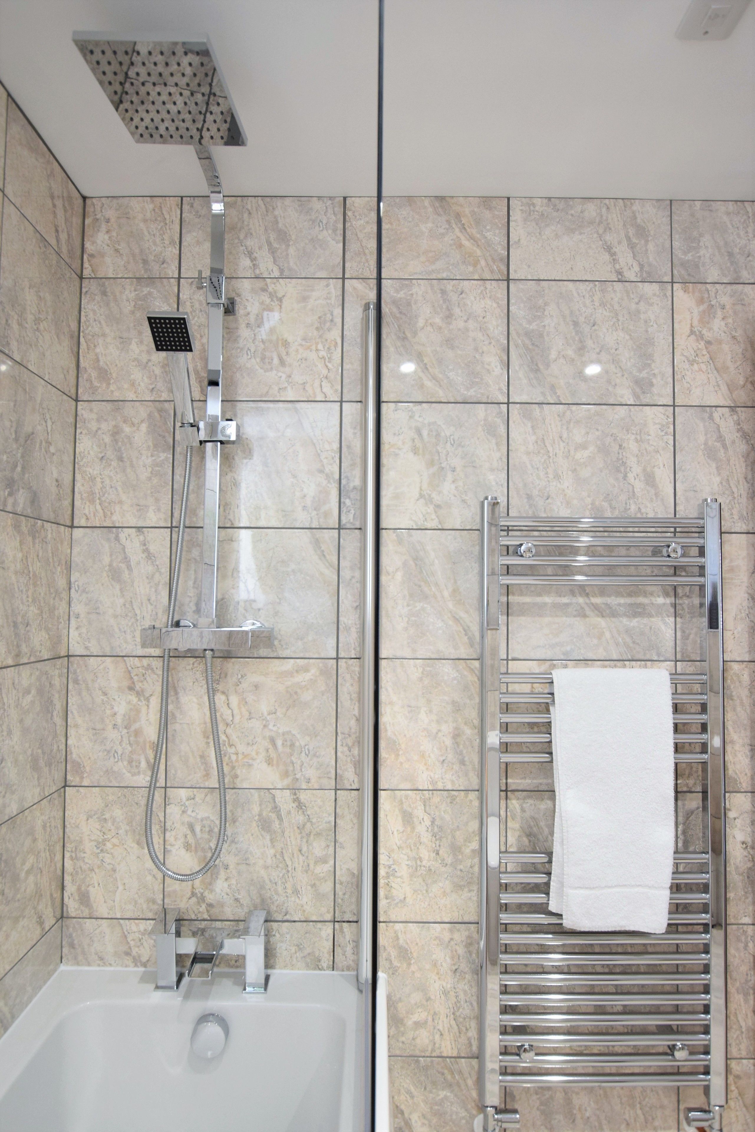 A modern bathroom with a shower, a bathtub, and a towel rack.