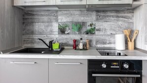 A modern kitchen with grey cabinets, a black sink, and a built-in oven. - Ares Aparthotel (Cluj-Napoca)