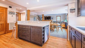 Una cucina moderna con mobili in legno, una grande isola e un'area pranzo con tavolo e sedie.