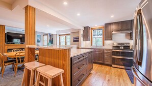 Una cucina moderna con dettagli in legno, un'isola grande ed elettrodomestici integrati.
