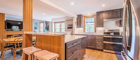 Une cuisine moderne avec des éléments en bois, un grand îlot central et des appareils électroménagers intégrés.