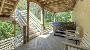 Una terrazza in legno con vasca idromassaggio, ringhiere bianche e una scala.