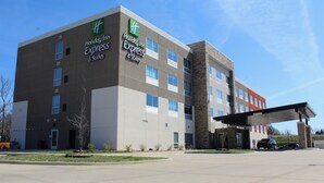 Ein Holiday Inn Express Gebäude mit modernem Design, das eine Kombination aus Ziegel- und Betonfassaden, zahlreichen Fenstern und einem überdachten Eingangsbereich zeigt.