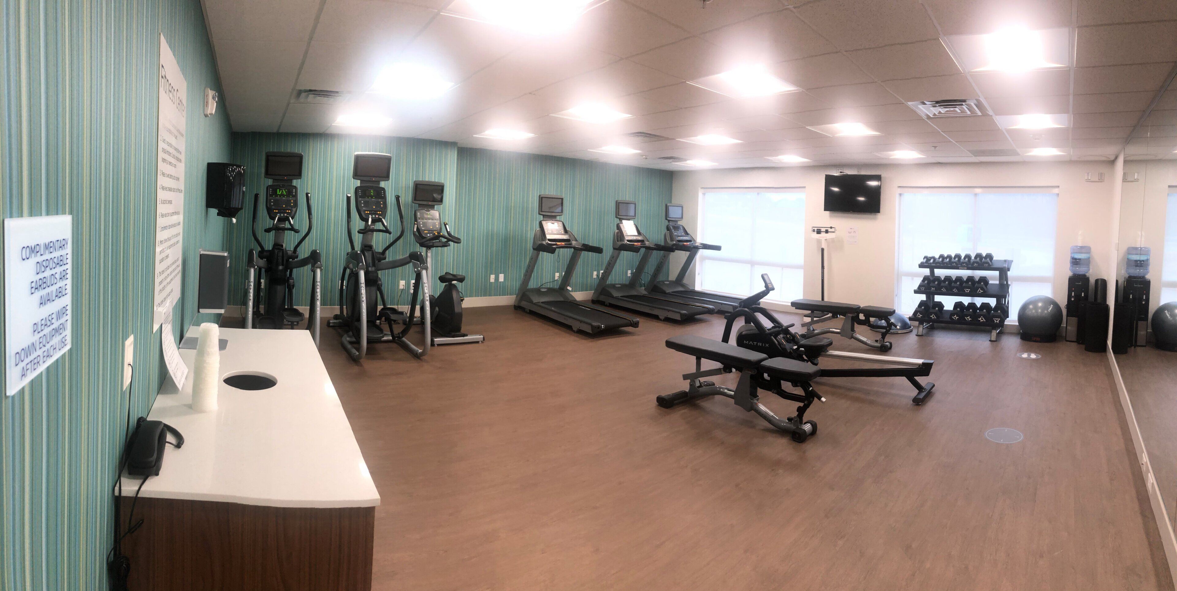 A gym with treadmills, elliptical machines, and free weights.