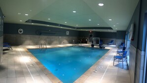 Ein Schwimmbecken mit deutlichen Bahnmarkierungen, einem Rettungsschwimmerstuhl und einer Schwimmhilfenanlage.