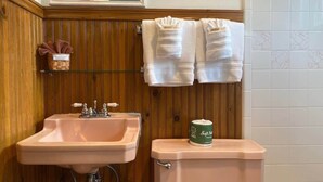 Ein Badezimmer mit einem Holzkosmetikschrank, einem Waschbecken, einer Toilette und zwei Handtüchern, die an der Wand hängen.