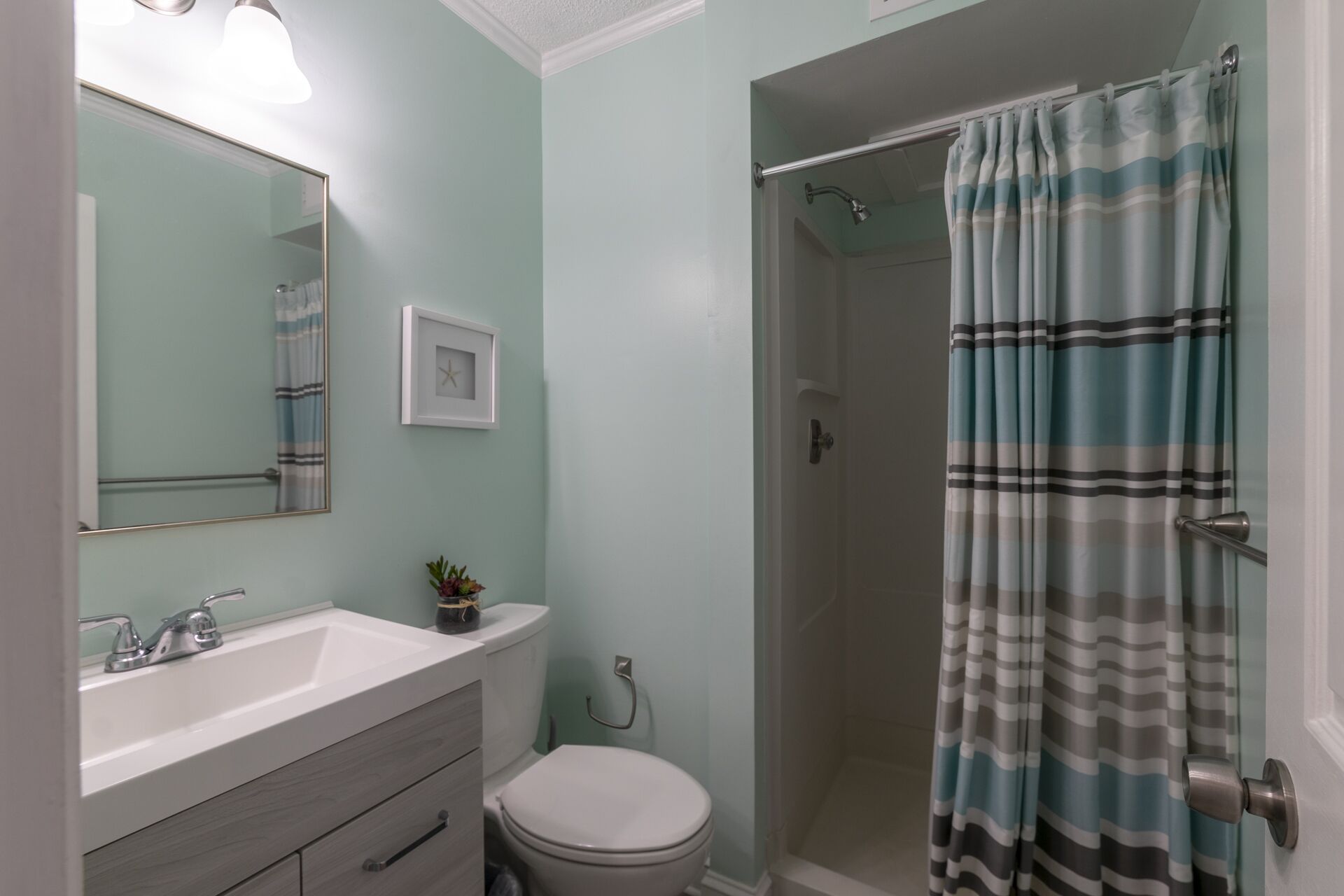 Une salle de bain équipée d’une douche, de toilettes, d’un lavabo et d’un miroir.