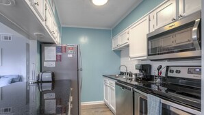 A compact kitchen with stainless steel appliances, a microwave, and a dishwasher. - Waipani E13 - 2BR Charming Condo! Across from Beach in Ocean Drive! (North Myrtle Beach)