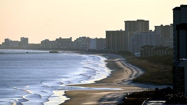 A coastal cityscape with a beach, high-rise buildings, and a pier. - Waipani E13 - 2BR Charming Condo! Across from Beach in Ocean Drive! (North Myrtle Beach)