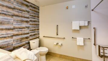 A modern bathroom with a toilet, bidet, and handrails.