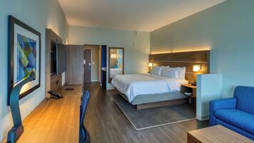 Ein Hotelzimmer mit Bett, Nachttisch, Stuhl, Schreibtisch und einem großen Spiegel.