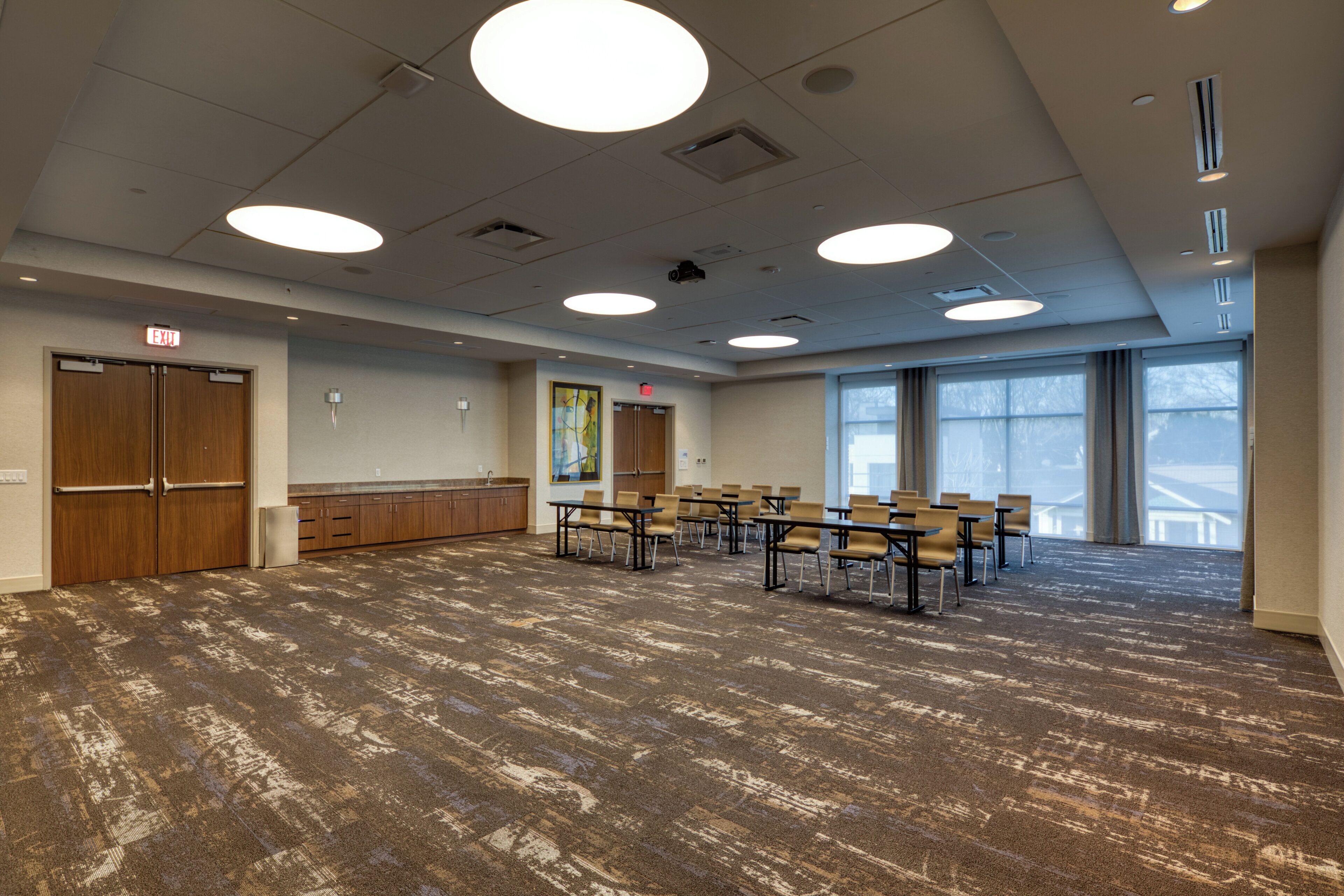A conference room with a carpeted floor, wooden cabinets, a large window, and a door marked 'EXIT'.