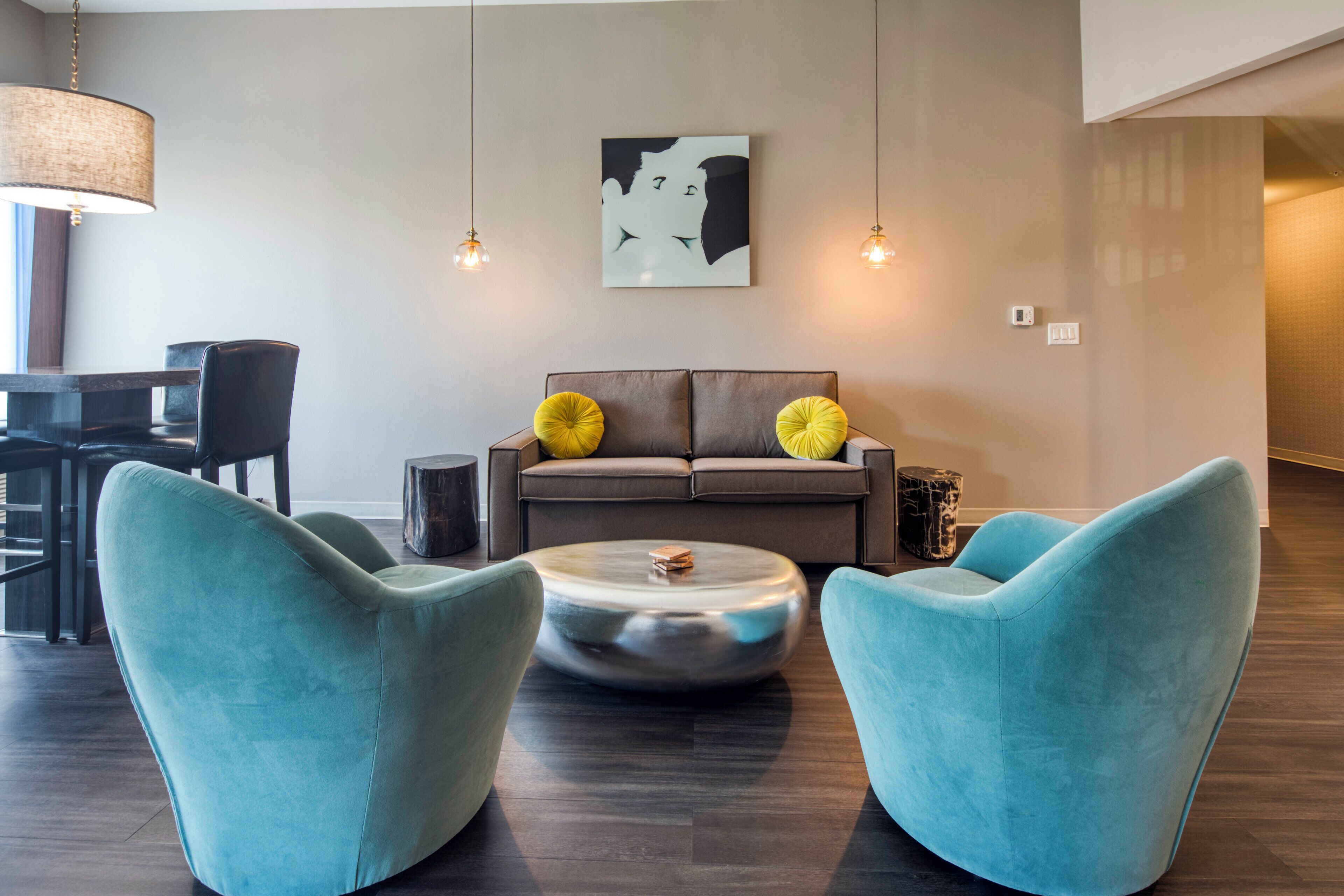 A modern living room with a sofa, two armchairs, a coffee table, and a wall-mounted artwork.