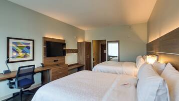 A hotel room with two beds, a desk with a computer, a TV, and a framed picture on the wall.