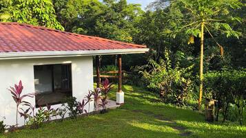 Une maison moderne avec un toit rouge, entourée d’une végétation luxuriante et d’une pelouse bien entretenue.