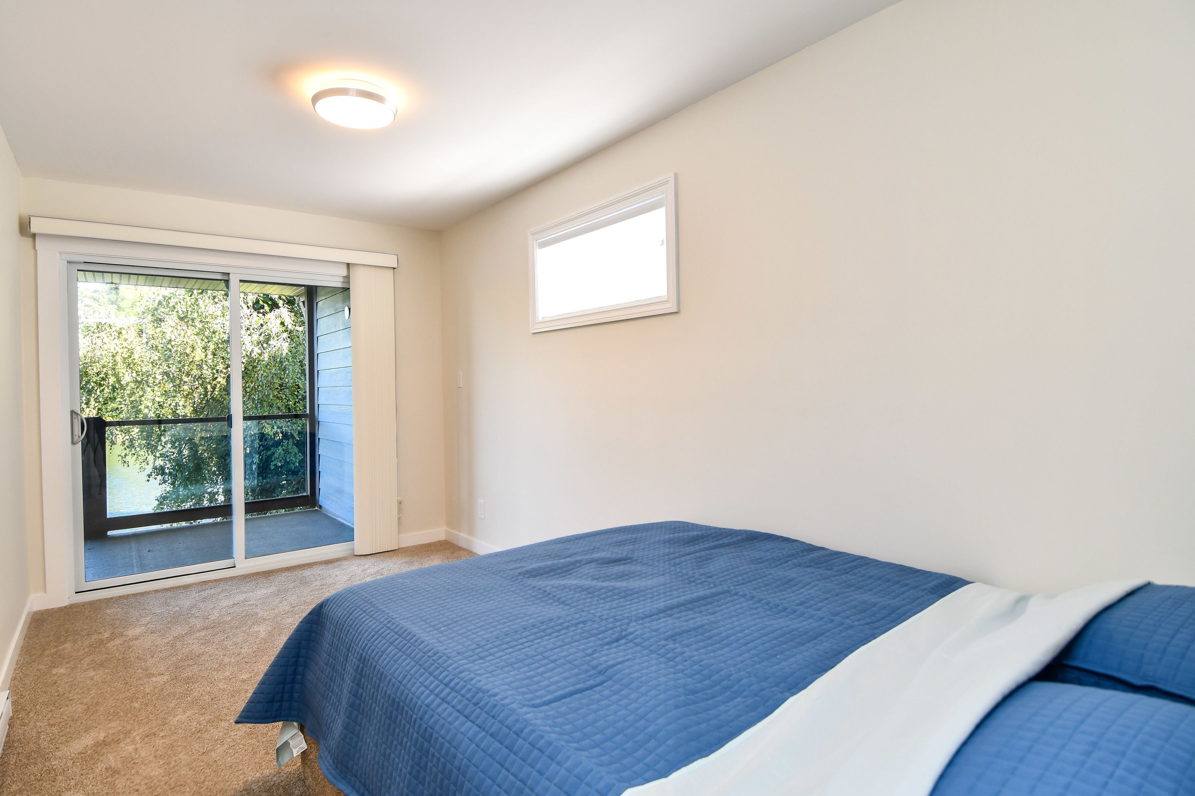 Une chambre à coucher avec un lit, une fenêtre et une porte donnant sur un balcon.