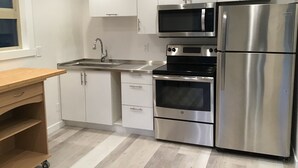 Una cocina moderna con electrodomésticos de acero inoxidable, armarios blancos y encimera de madera.