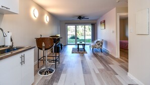 Una cocina moderna con un taburete de bar, un comedor con mesa y sillas, y vistas al exterior a través de un ventanal.
