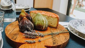 A wooden board with figs, a cheese, and rosemary on a table.