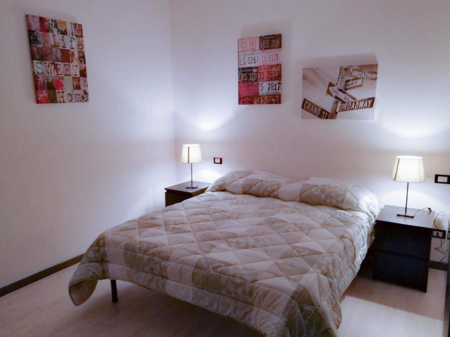 Un dormitorio con cama, dos mesitas de noche y decoración en la pared.
