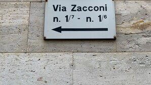 A directional sign on a stone wall indicating Via Zacconi with a directional arrow pointing left. - Fiera051 - Affittacamere (Bologna)