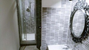 A bathroom with a glass shower enclosure, a white sink, and a mirror with a decorative frame. - Fiera051 - Affittacamere (Bologna)