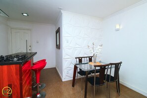 Compact kitchen with gas stove, white cabinet, and dining area with glass table and four chairs.