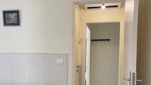A living room with a patterned sofa, a door leading to another room, and a wall-mounted light fixture. - Apartment in Jdeideh Beirut (Jdeideh)