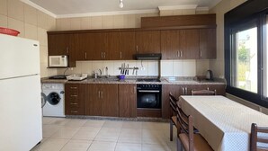 A kitchen with wooden cabinets, a built-in microwave, a sink, a stove, and a washing machine. - Apartment in Jdeideh Beirut (Jdeideh)