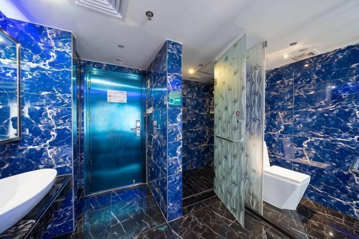 A modern bathroom with a marble sink, a glass-enclosed shower, and a marble wall.