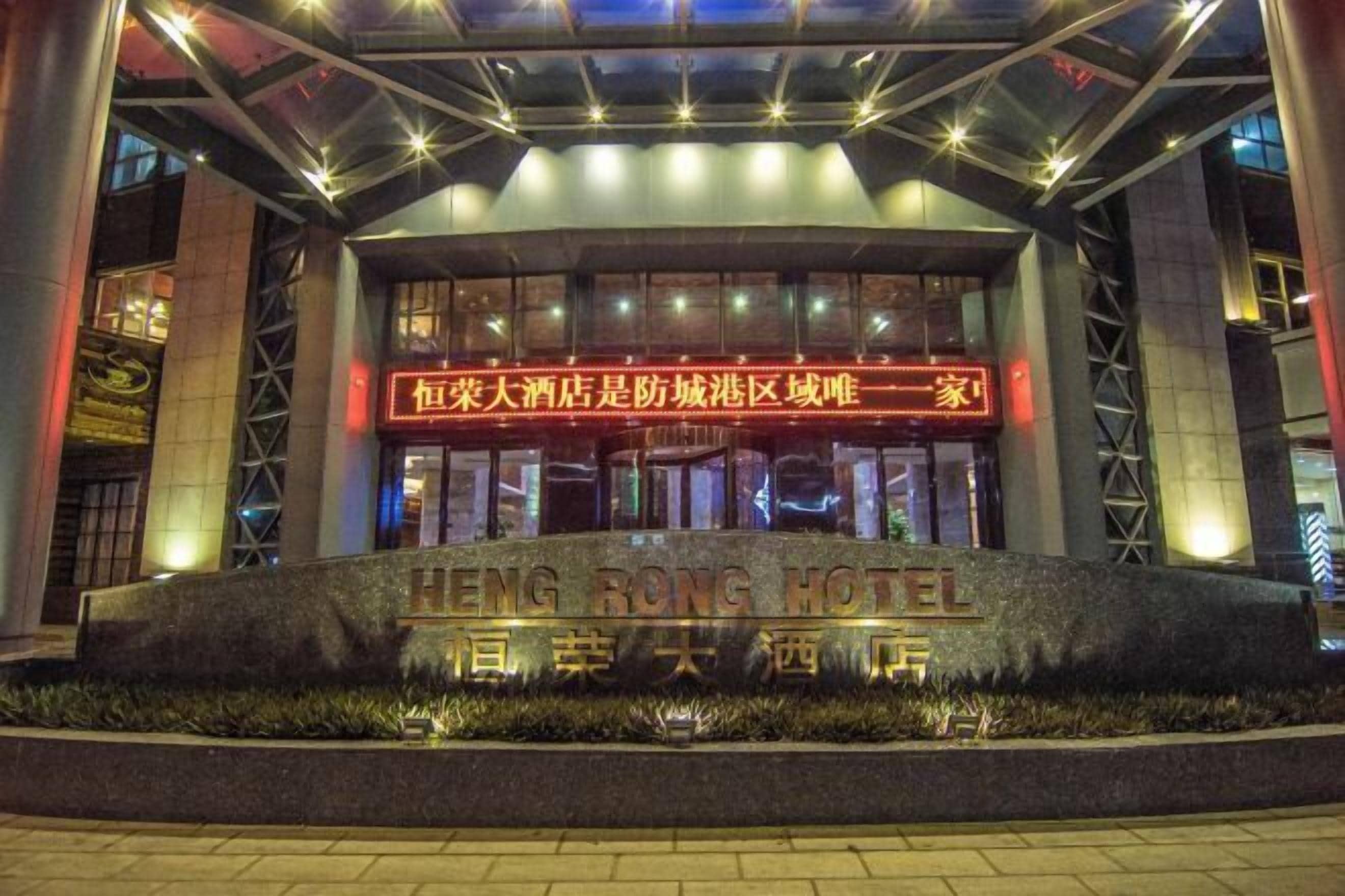 The exterior of the Heng Rong Hotel with illuminated signage and a stone base.